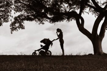 Stressed mother in silhouette pushing a stroller