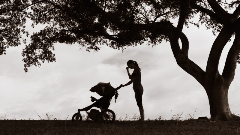 Stressed mother in silhouette pushing a stroller
