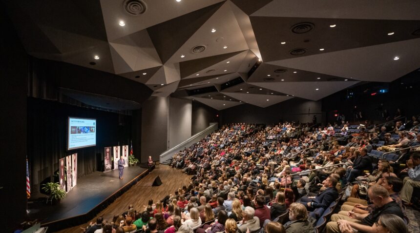 a photo of a crowd in Rudder Theatre with Interim President Mark A. Welsh III on the stage.