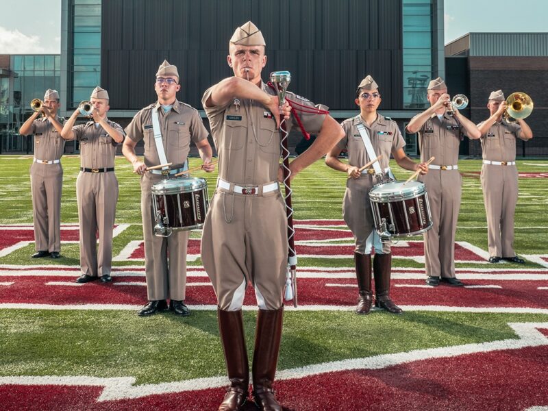 Cade Mahlen ’24 standing with other band members in formation on the Aggie Band practice field