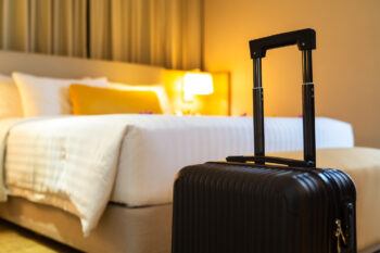 A black suitcase sitting at the end of a bed in a hotel room