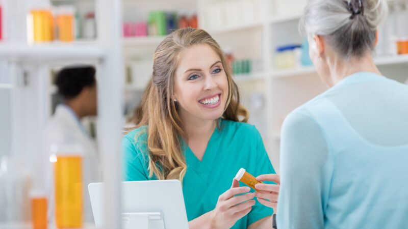 A photo of a woman in a pharmacy working with a customer.