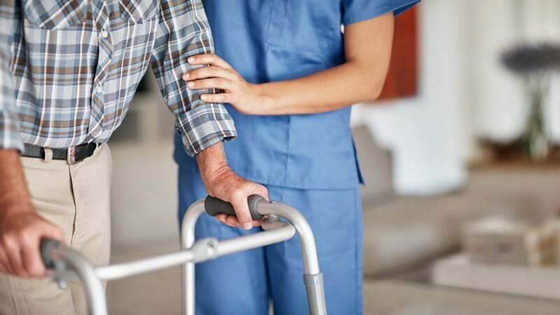 a health care worker helping a patient with a walker