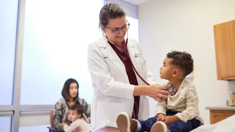 A photo of a doctor listening to a young boy's heartbeat with a stethoscope.