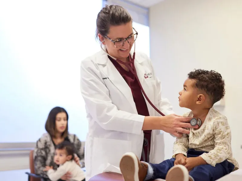 A photo of a doctor listening to a young boy's heartbeat with a stethoscope.