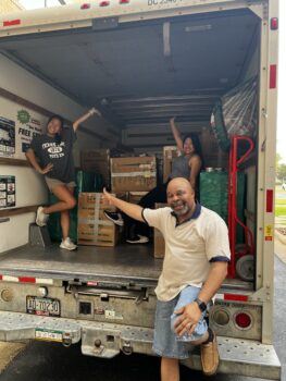 a photo of a man and two young woman smiling in the back of a moving truck filled with boxes