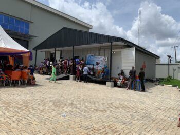 a photo of people gathered around two portable clinics linked by a metal building