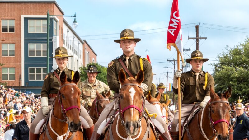 A photo of uniformed members of the Corps of Cadets on horseback in a parade.