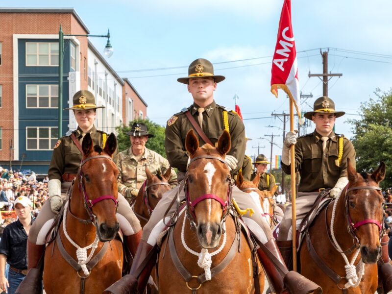 A photo of uniformed members of the Corps of Cadets on horseback in a parade.