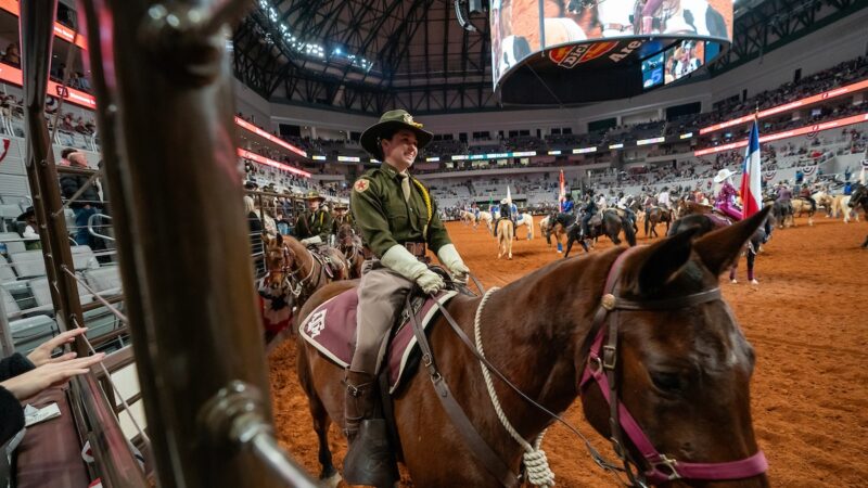 A cadet on a horse rides through the rodeo arena