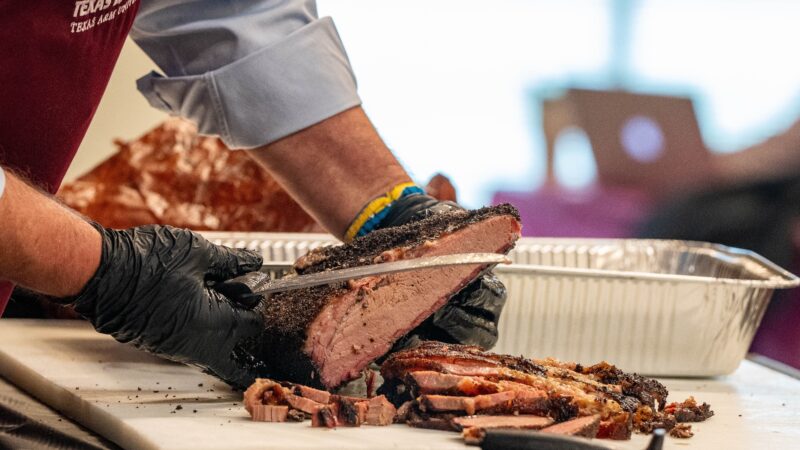 a photo of a smoked brisket being carved on a large cutting board