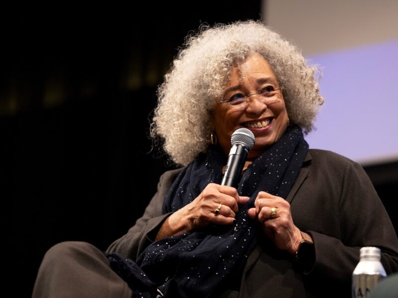 a photo of Dr. Angela Davis holding a microphone and smiling