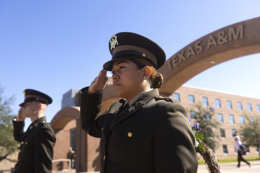 A photo of two cadets saluting during a ceremony outside the arches on the Texas A&M University campus.