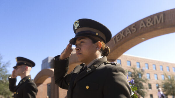 A photo of two cadets saluting during a ceremony outside the arches on the Texas A&M University campus.