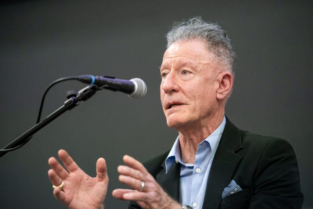 A photo of Lyle Lovett speaking into a microphone.