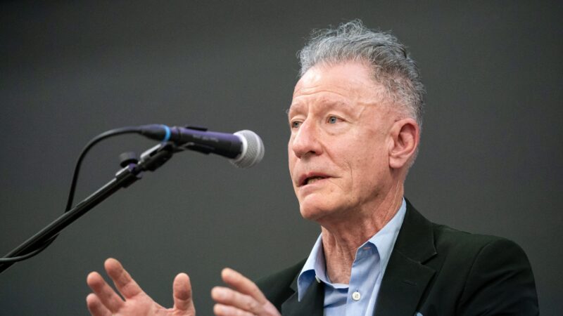 A photo of Lyle Lovett speaking into a microphone.