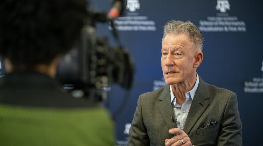 A photo of Lyle Lovett talking to the media.