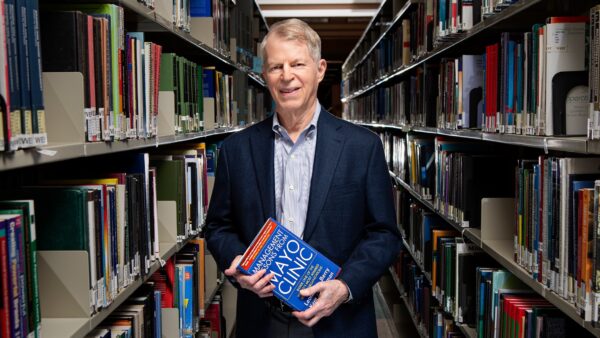 A photo of Dr. Leonard Berry standing among books in a library.