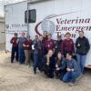 A photo of a group of people standing in front of a trailer from the Texas A&M University Veterinary Emergency Team.