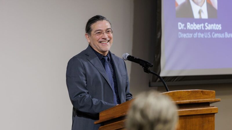 U.S. Census Director Robert Santos standing at the podium during his presentation at Texas A&M University