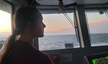 an Aggie student surveys the ocean view from the ship's bridge