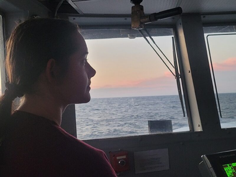 an Aggie student surveys the ocean view from the ship's bridge