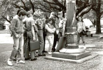 a group of students reading the Silver Taps names at the flagpole in 1987