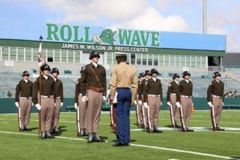 A photo of members of the Fish Drill Team standing at attention on a football field.