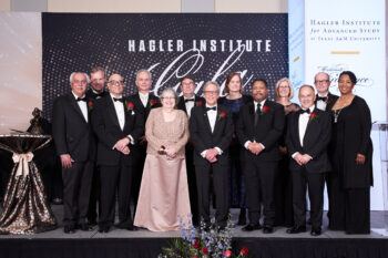 A photo of 13 people on a stage at a black-tie event.