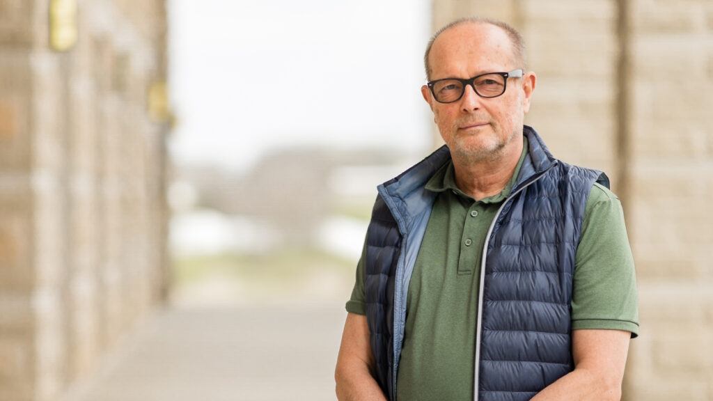 A photo of a man wearing glasses standing outside.