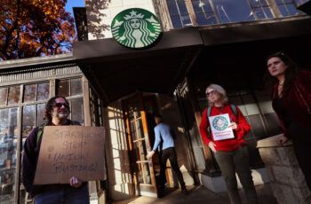 Protesters holding signs stand outside of a Starbucks store.