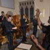 A conductor leading a trombone choir in a church.