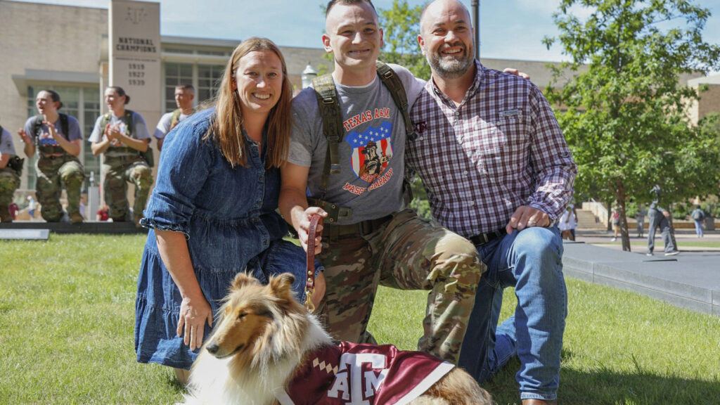 A cadet kneeling along with his parents with Reveille X on the Texas A&M University campus.