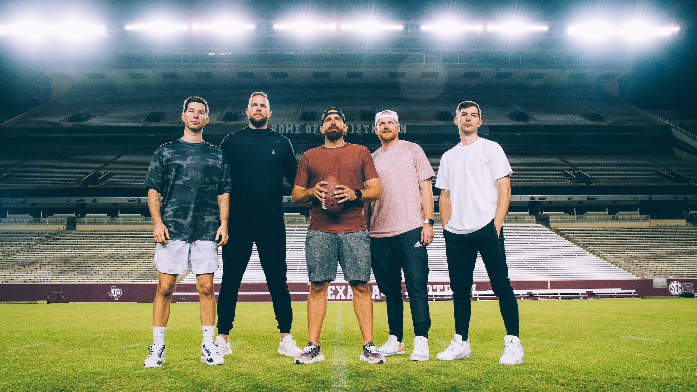 Members of Dude Perfect standing on Kyle Field with stadium lights in the background.