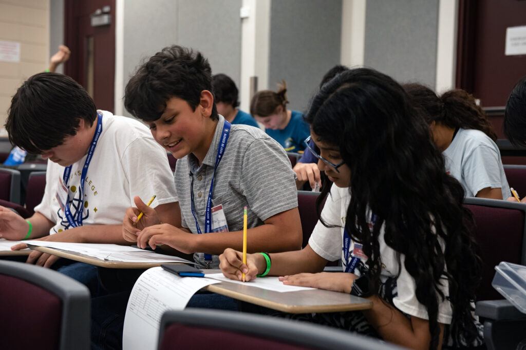 Competitors in a youth science competition take an exam in a classroom.