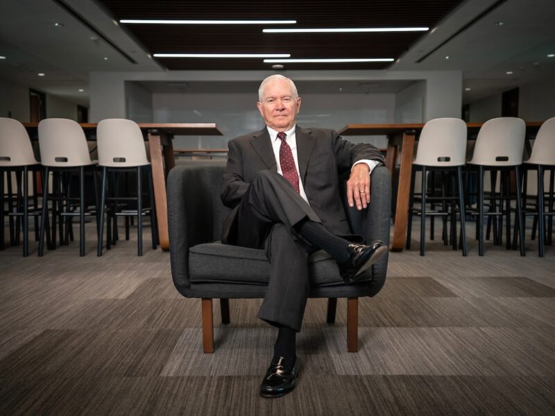 Robert Gates sits in a chair in a common area of the Bush School.