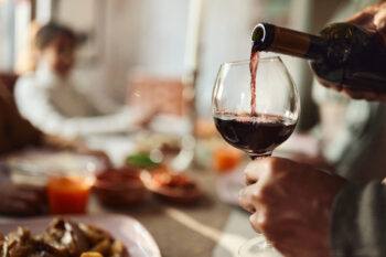 close up of a man pouring red wine in a glass