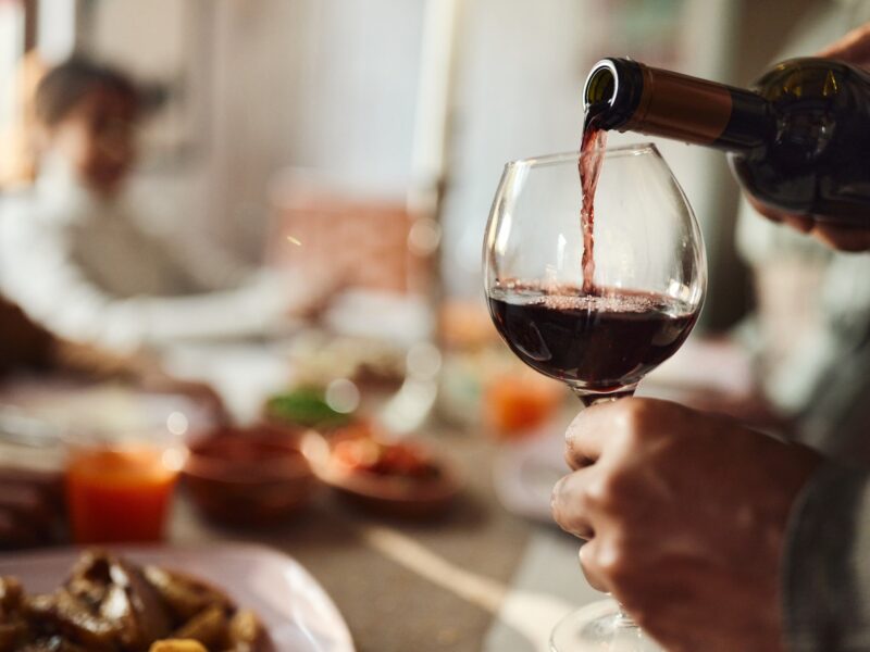 close up of a man pouring red wine in a glass