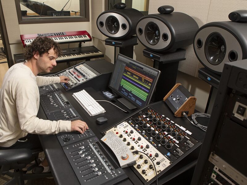 A man operates audio equipment in a recording studio.