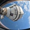 An exterior view of the Starliner capsule from space with Earth in the background