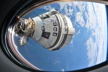 An exterior view of the Starliner capsule from space with Earth in the background