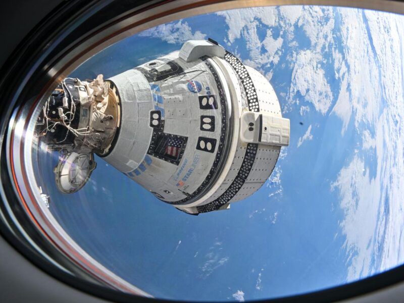 An exterior view of the Starliner capsule from space with Earth in the background