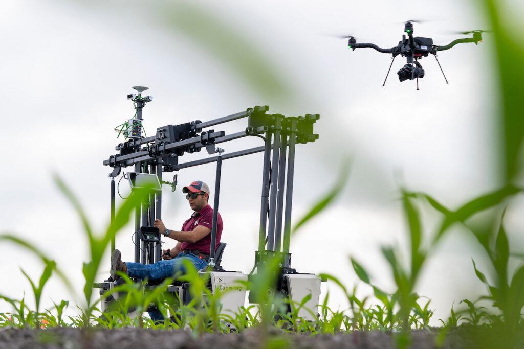 A man demonstrating machinery and a drone in a corn field