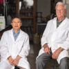 Two researchers in white coats seated in a lab