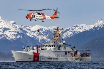 A photo of a U.S. Coast Guard cutter and helicopter conducting training exercises in Alaska.