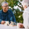 Chess, nature and retirement with senior friends playing a board game while bonding outdoor during summer.