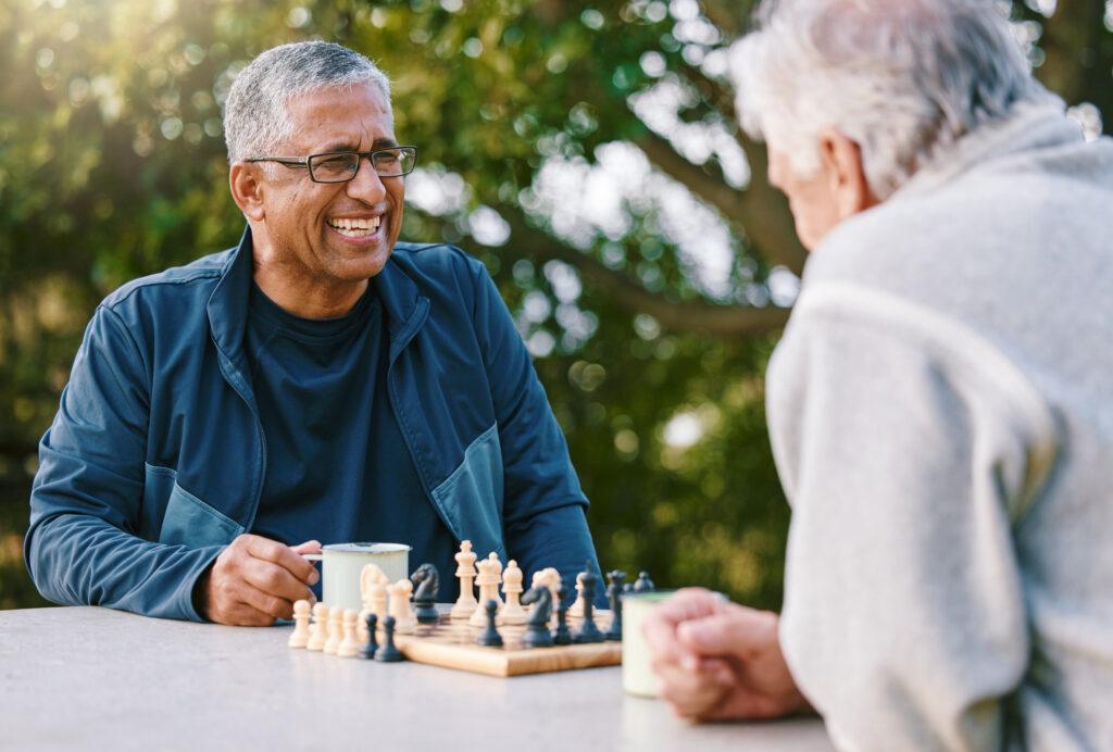 Chess, nature and retirement with senior friends playing a board game while bonding outdoor during summer.