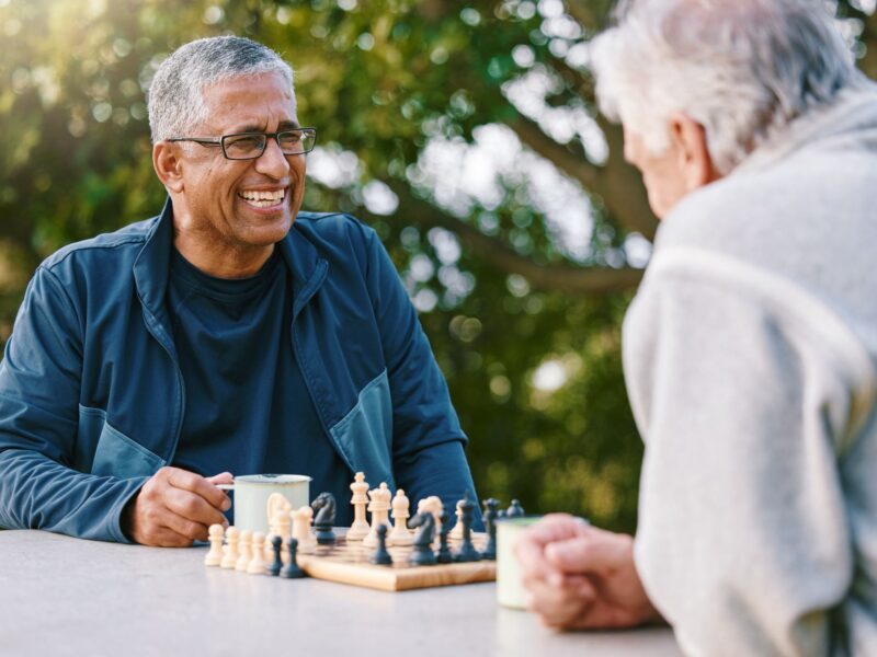 Chess, nature and retirement with senior friends playing a board game while bonding outdoor during summer.