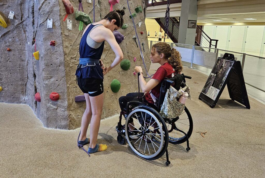 two clinic participants preparing to climb the rock wall at the Rec Center during training before launch