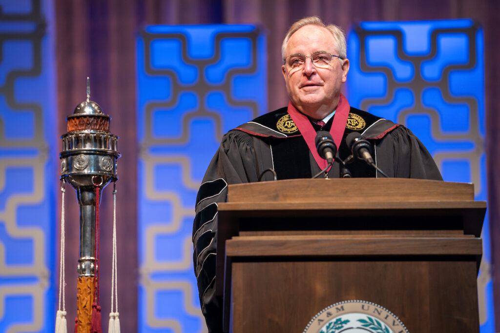 Mark Welsh speaking at a podium in academic regalia at his presidential investiture